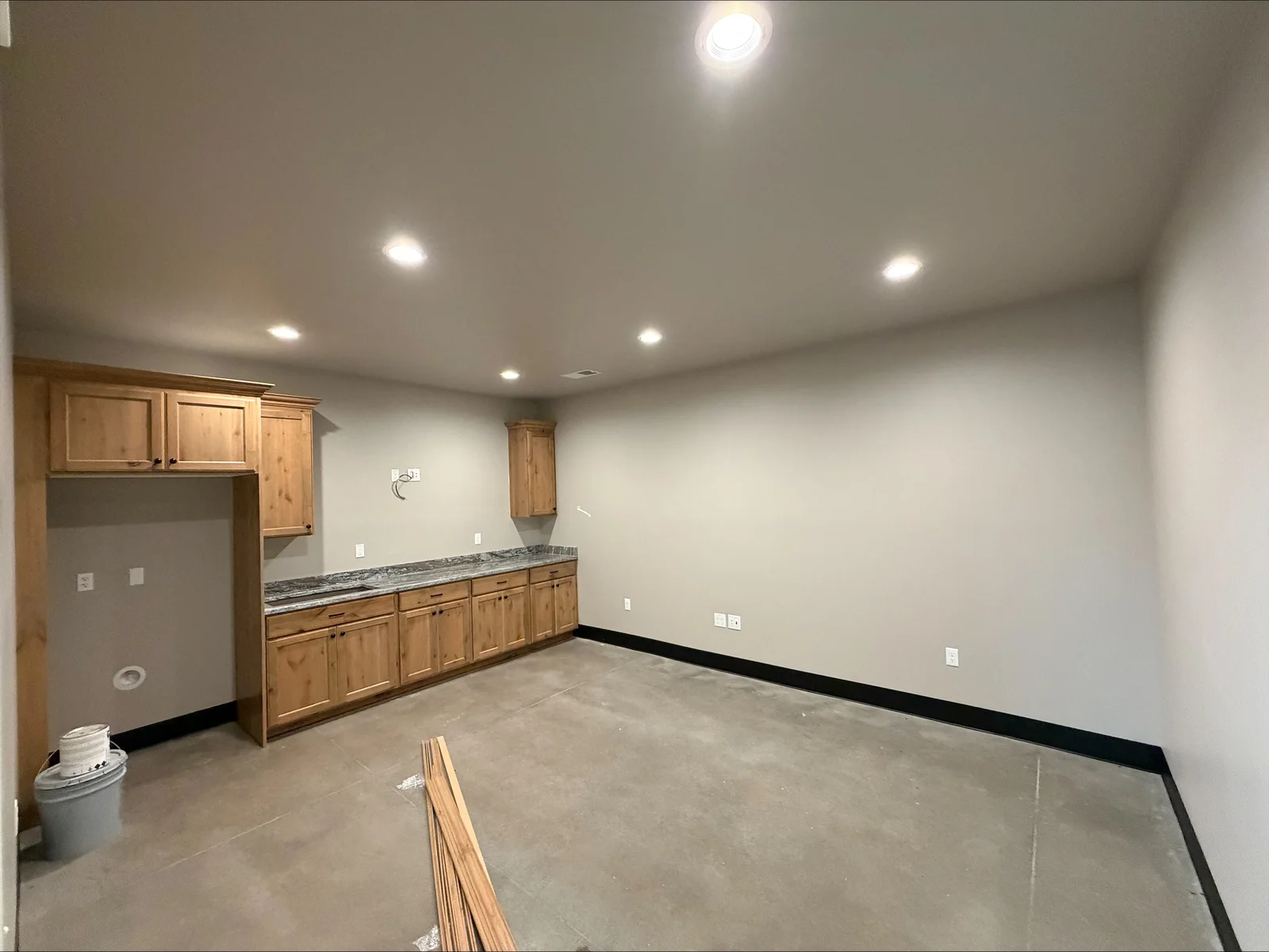 Basement electrical installation with recessed LED lights, outlets, and wiring in drywall