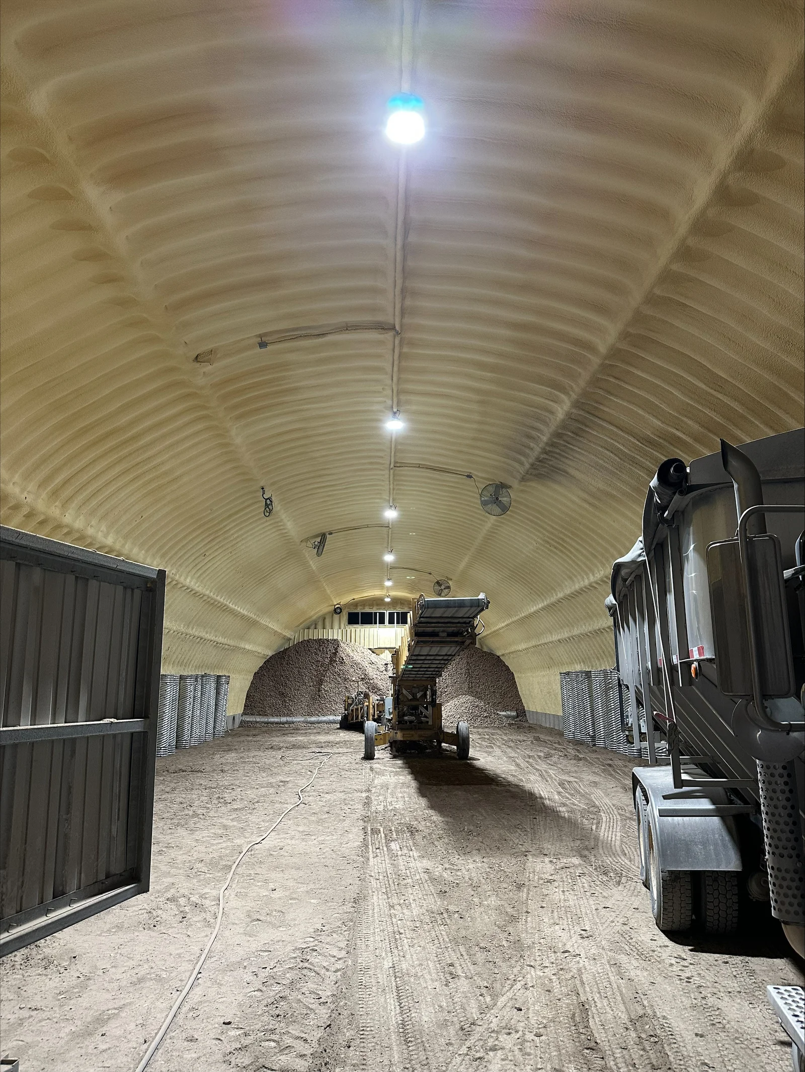 LED lighting fixtures installed in arched metal agricultural storage tunnel with conduit routing