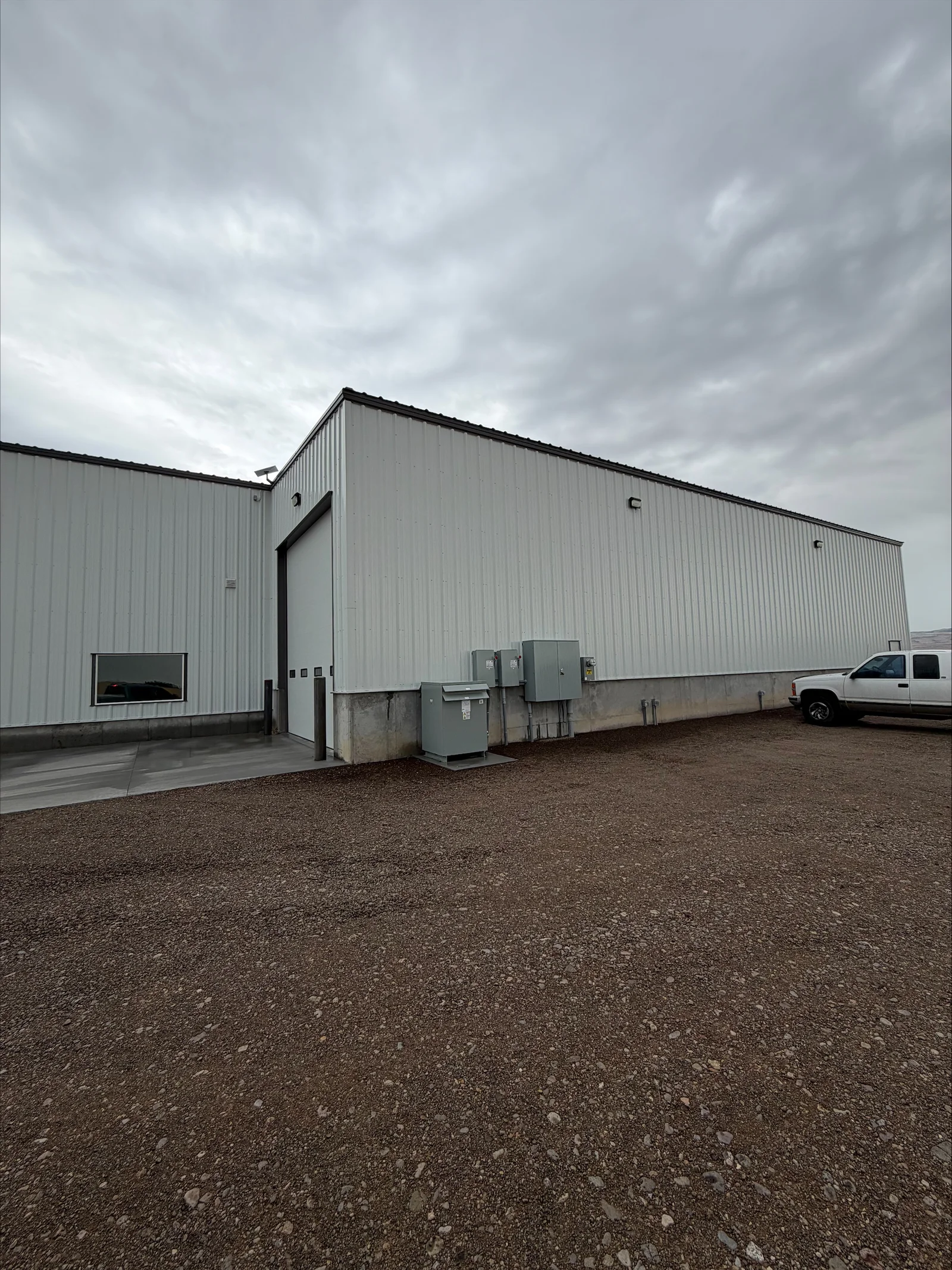 Metal building exterior with installed electrical service panels and disconnect boxes on concrete pad