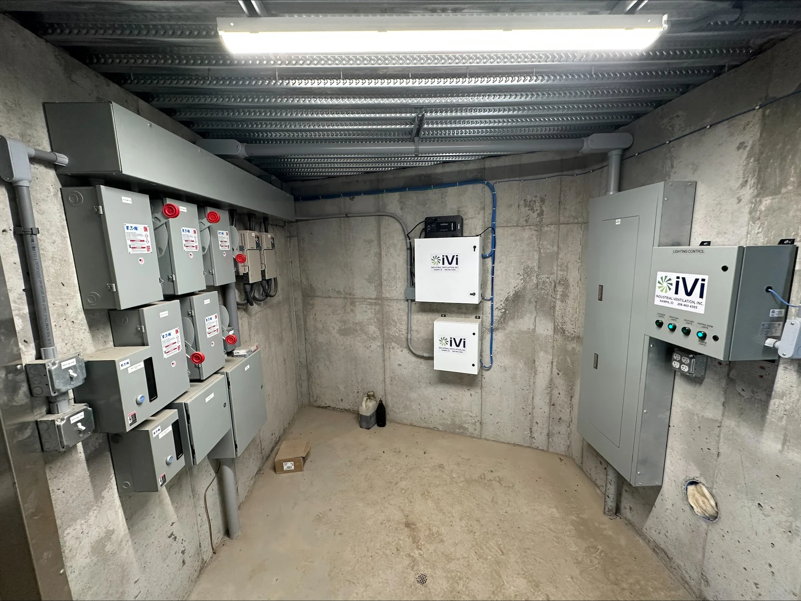 Electrical room with disconnect switches, iVi inverters, metal decking ceiling, and blue conduit routing