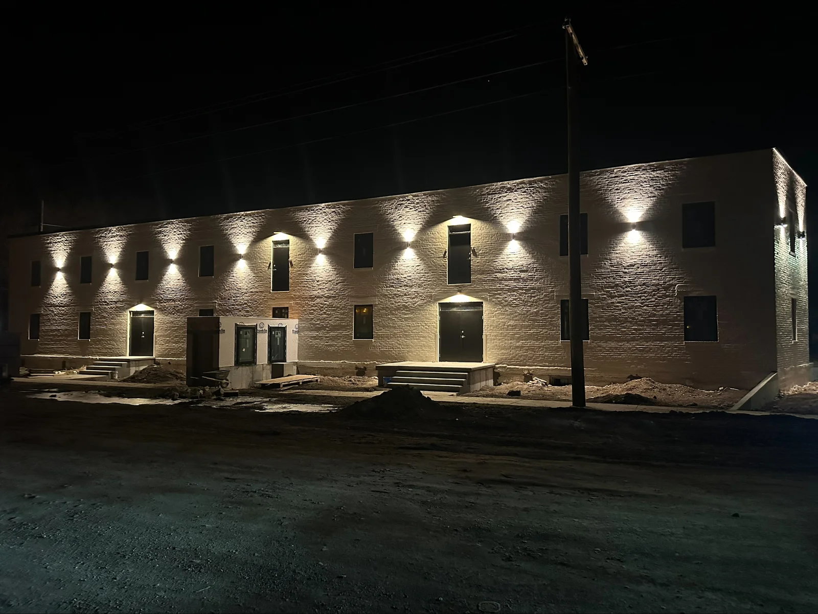 Brick commercial building with uplighting fixtures illuminating textured facade at night