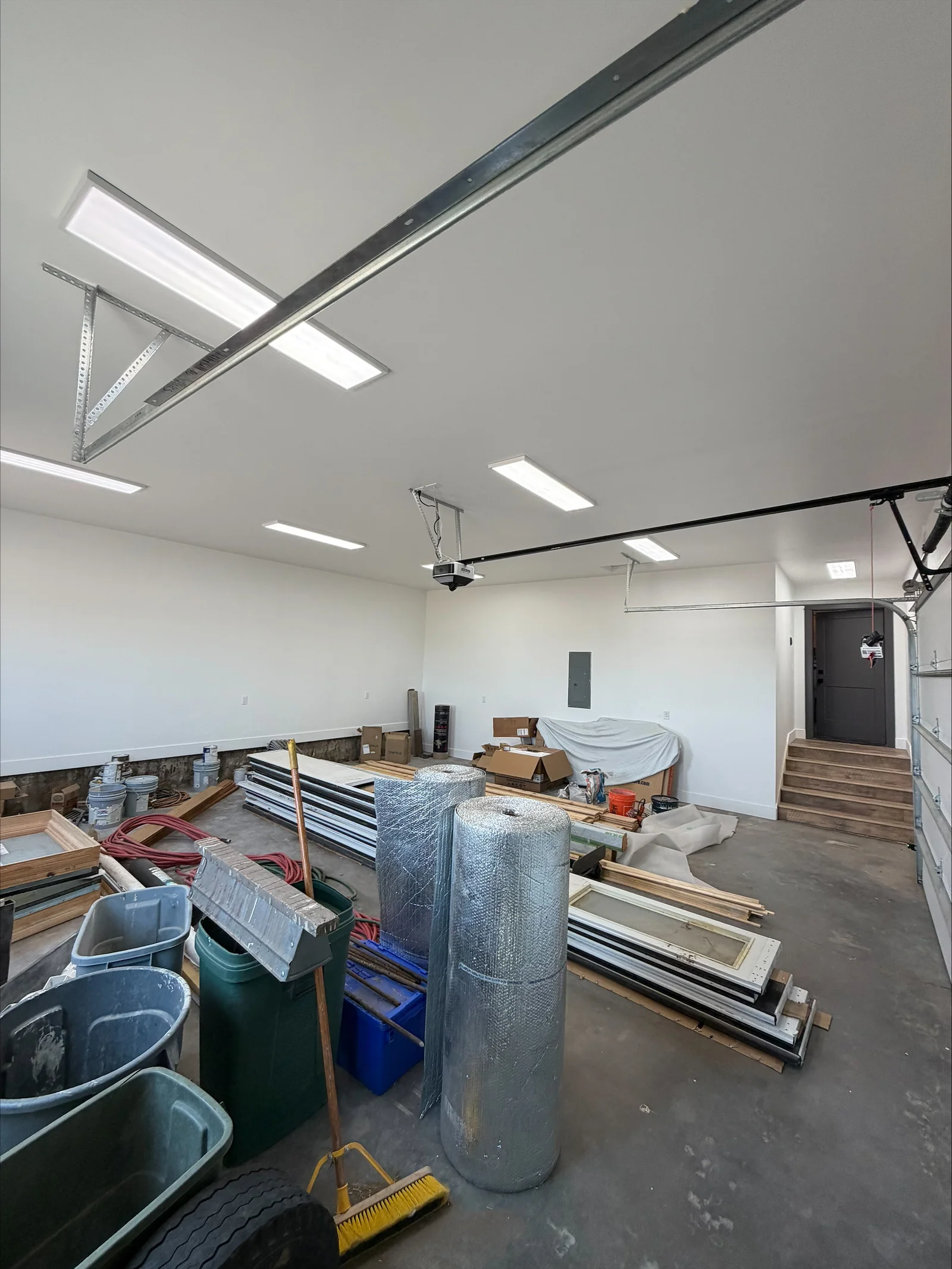 Commercial garage with recessed LED panels and linear light fixtures installed in drywall ceiling