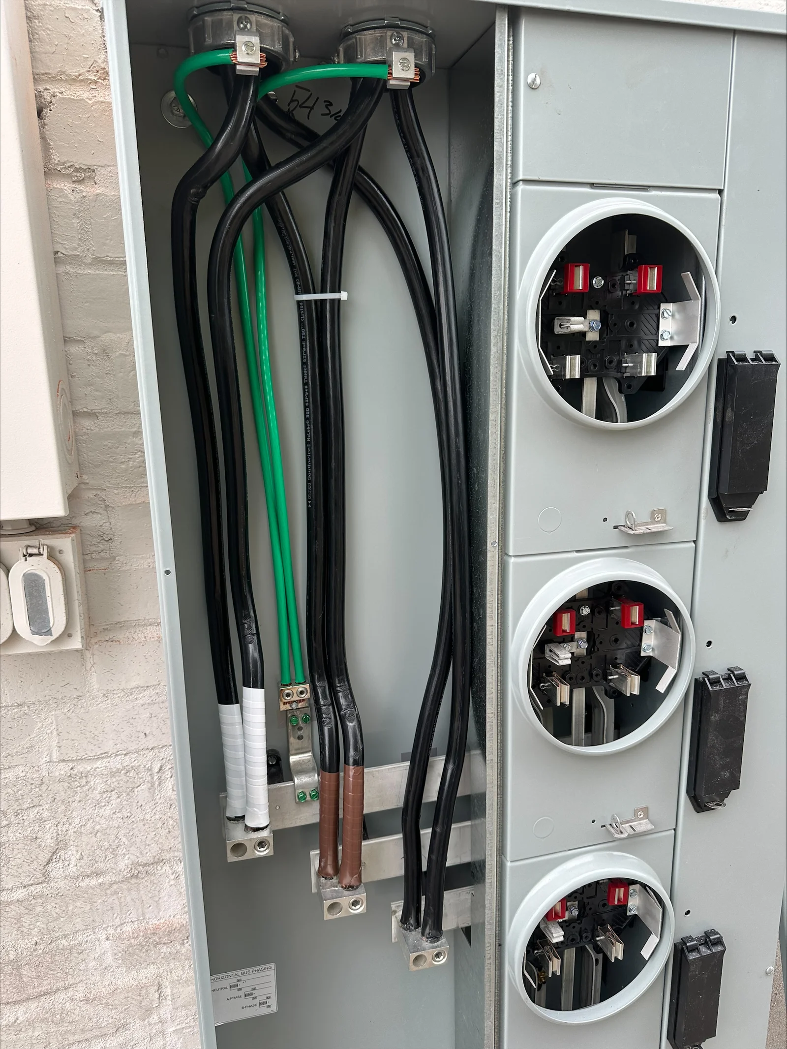 Three-phase service panel with three 200-amp disconnects, copper bus bars, and black/green power conductors