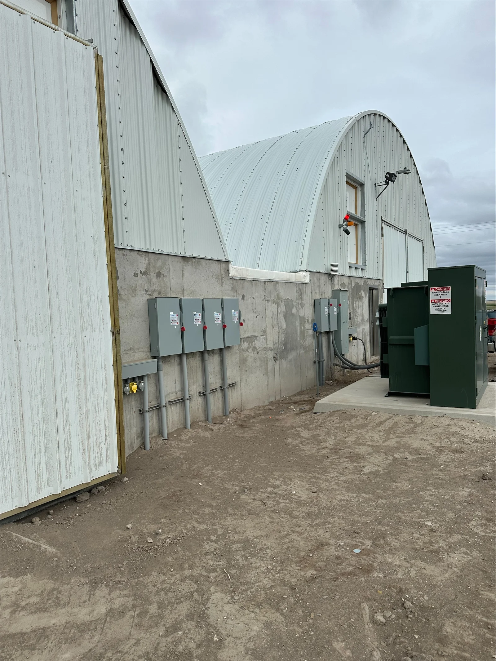 Electrical disconnect switches and panels mounted on concrete foundation of metal agricultural building