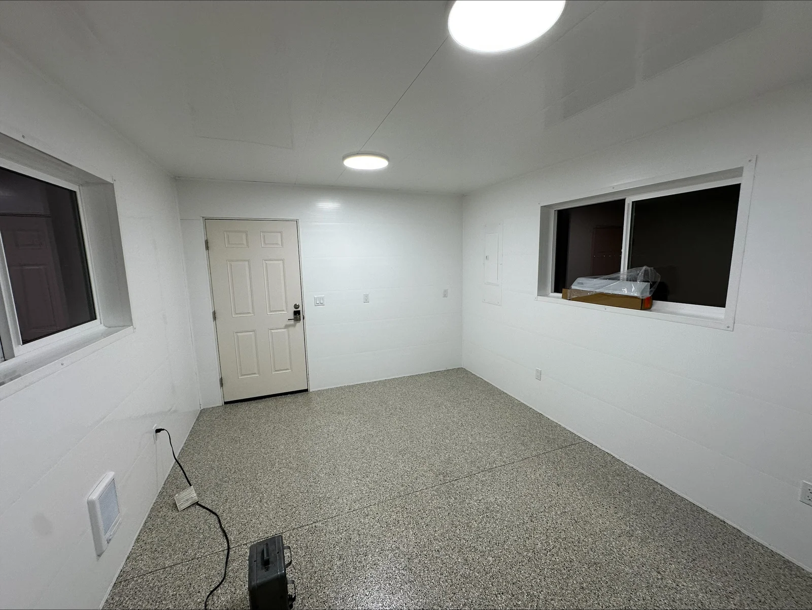 Finished basement with recessed LED ceiling lights, white drywall walls, electrical outlets, and gray epoxy flooring