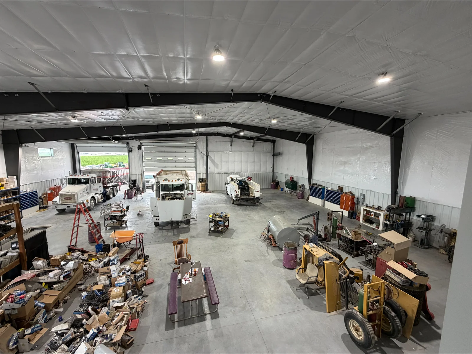 Commercial workshop with LED ceiling lights, steel beams, and concrete floor