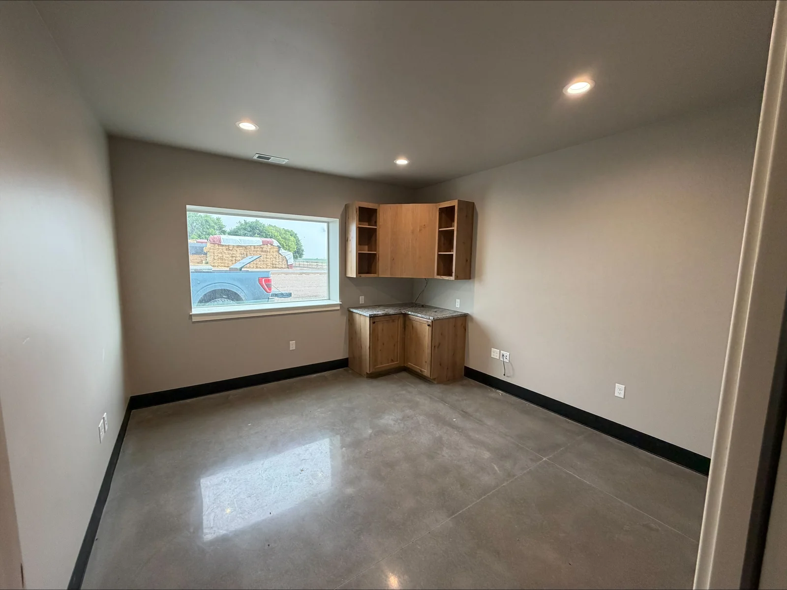 Commercial kitchen with recessed LED lighting, wood cabinetry, concrete flooring, and electrical outlets installed in drywall