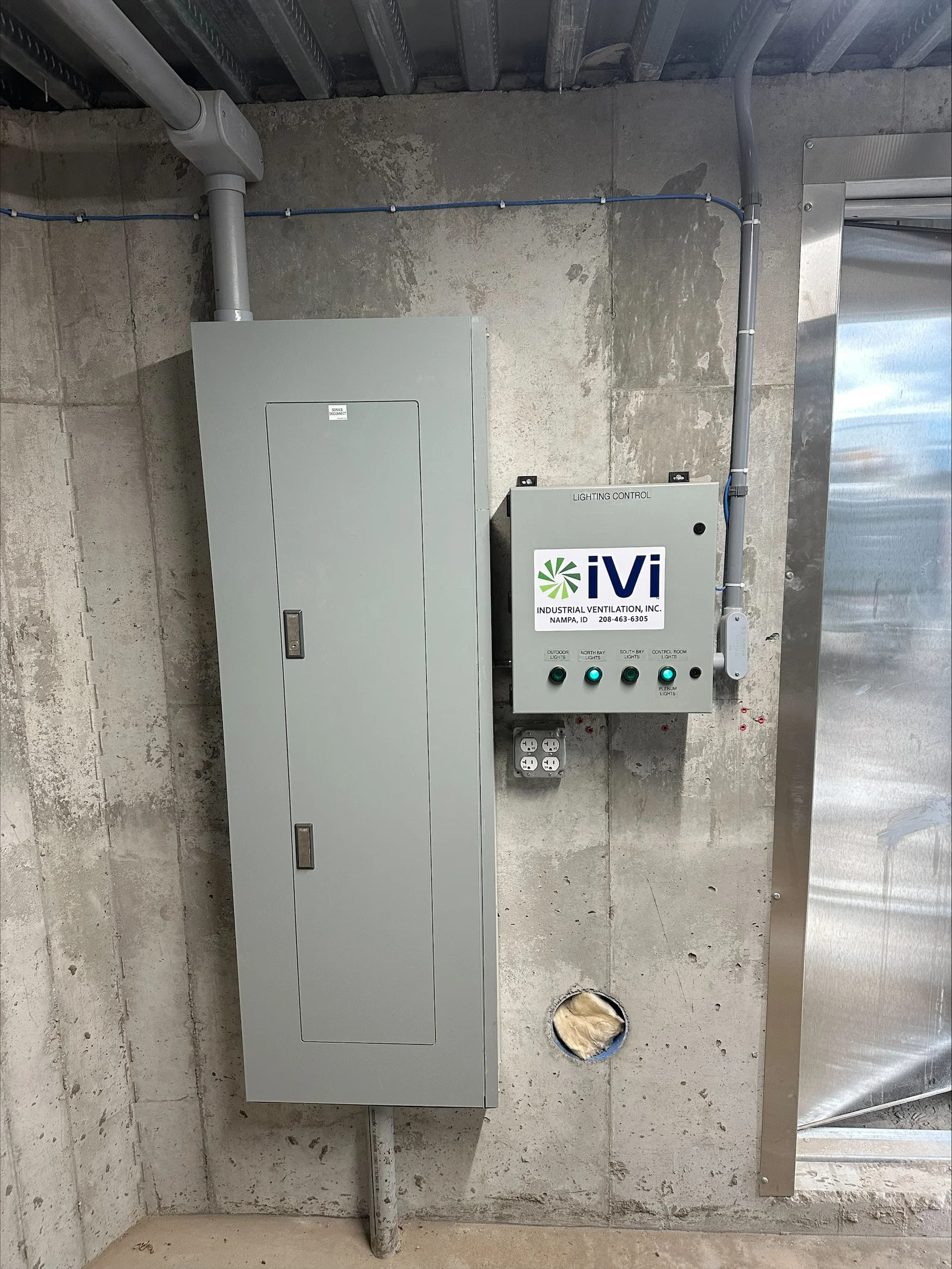 Control panel with lighting switches and ventilation controls mounted on concrete basement wall
